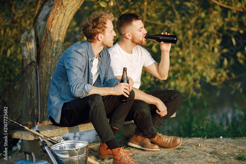 Canvastavla Two men fishing near the river and drinking a beer