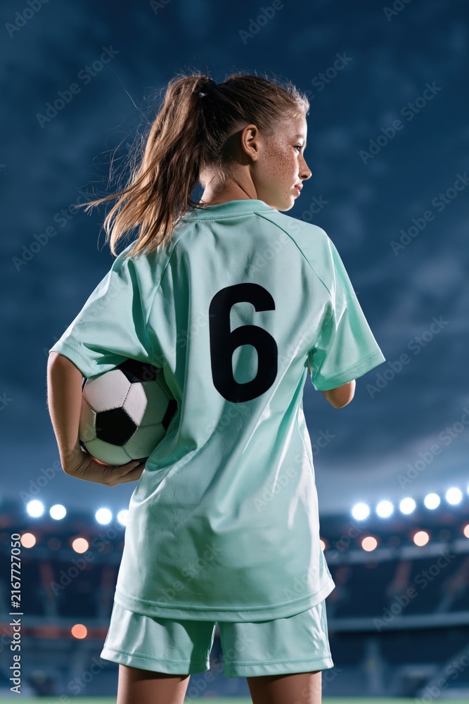Naklejka premium Young female soccer player wearing number 6 in stadium at night holding a ball for team poster and banner background design