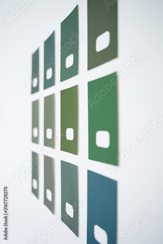 Green paint samples in different shades arranged on white wall for comparison