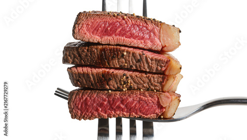 Принти на полотні Stack of four medium-rare grilled steak slices seasoned with pepper impaled on a