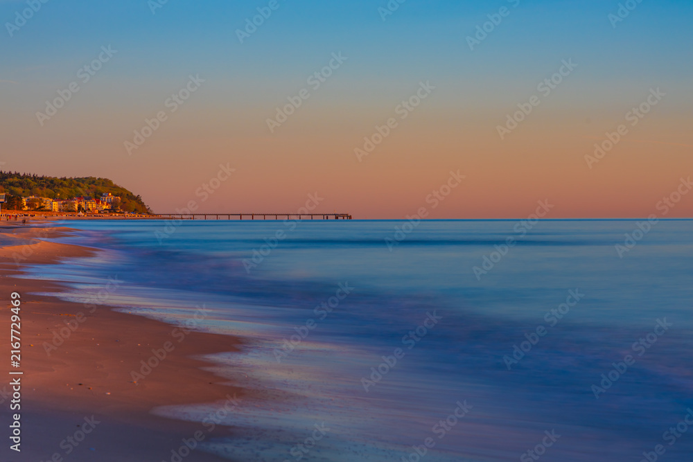 Obraz premium Panoramic View Of Empty Sandy Beach At Dawn With Distant Pier Silhouette