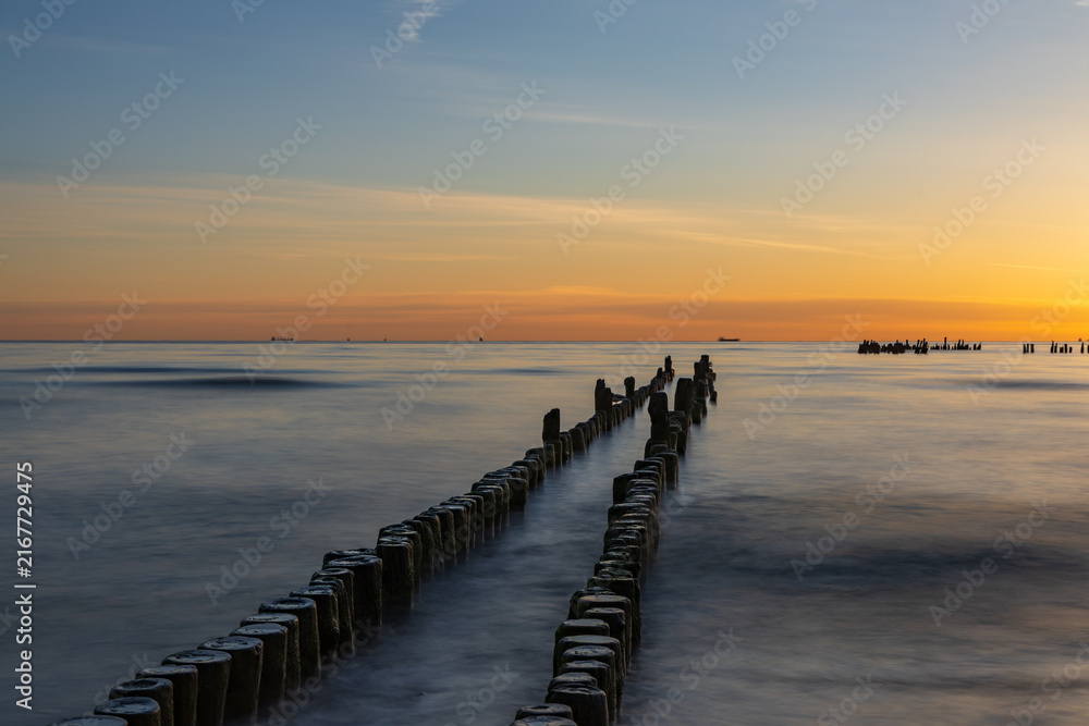Obraz premium Deep Perspective Long Exposure Landscape Of Breakwater Piles In Calm Ocean