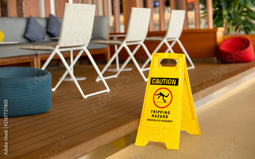 Foto Yellow caution sign marking a tripping hazard beside lounge chairs in a modern c