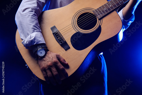 Bild auf Leinwand Young man playing guitar on black background