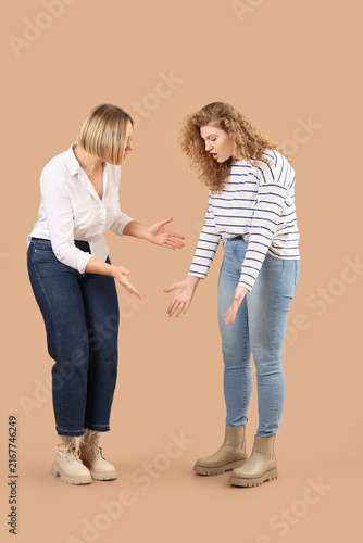 Beautiful shocked women in stylish jeans on beige background