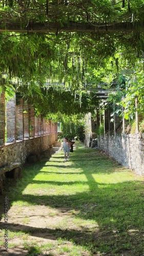 Happy young girl running through a green wisteria tunnel