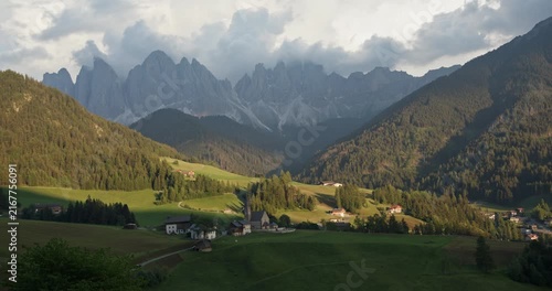 Santa Maddalena village under moving cloud shadows beneath the Odle peaks in Val di Funes, Dolomites, Italy