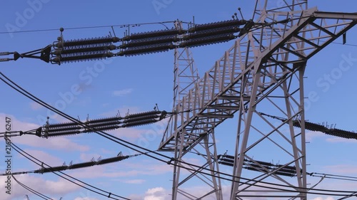 Close-up of high voltage power transmission line insulators and metal lattice pylon in electrical grid