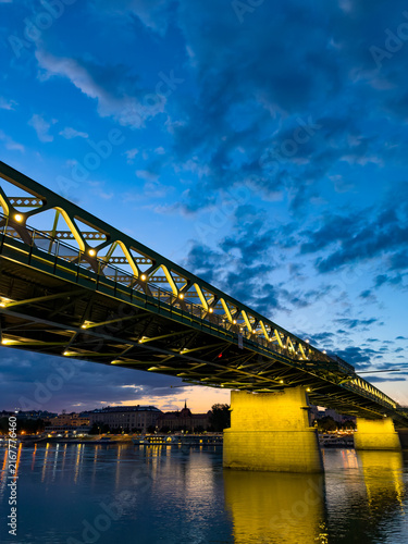 Bild auf Leinwand Bridge lit up at dusk by the river
