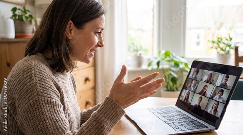 Woman smiling and gesturing while participating in a video conference call with multiple people