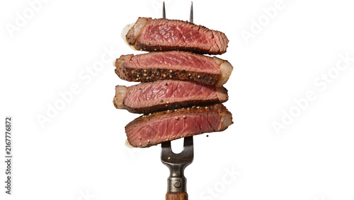 фотографія Stack of four medium-rare steak slices seasoned with pepper impaled on a metal f