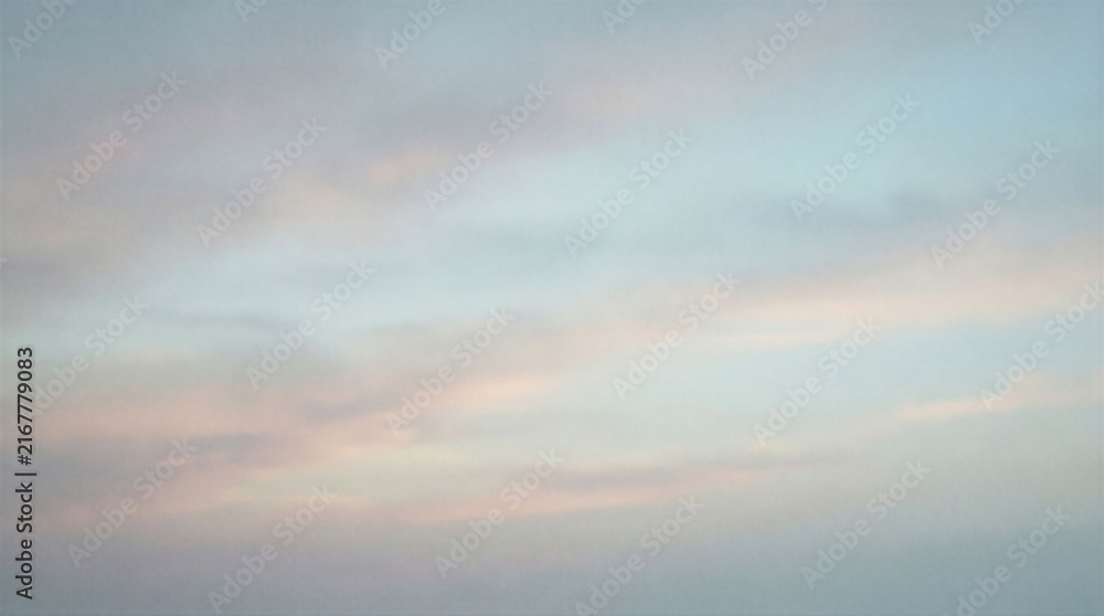 Fototapeta premium Sky shows soft clouds with shades of pink and blue as day begins to break. The scene captures the early morning light gently illuminating the horizon.