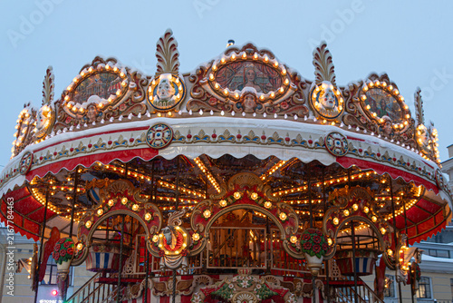 Beautiful vintage carousel illuminated by yellow and red lights in the middle of the night in the city. Merry-Go-Round. Leisure time and fun.  No people around. Dark blue sky.