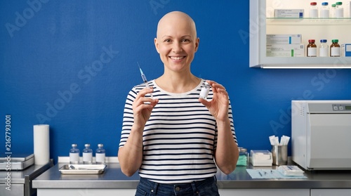 Smiling healthcare professional holding syringe and vial in medical office setting