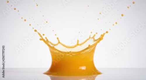 Vibrant orange liquid creating a crown-like splash against a white backdrop