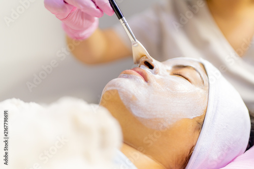 Woman receiving professional facial mask treatment