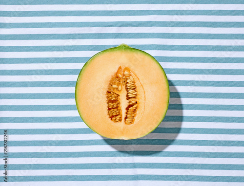 Halved Ripe Melon on Striped Tablecloth in Sunny Light Top View