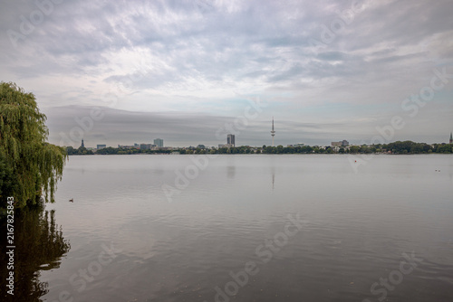 Panoramic view across the Außenalster lake under a soft evening sky in Hamburg, Germany.