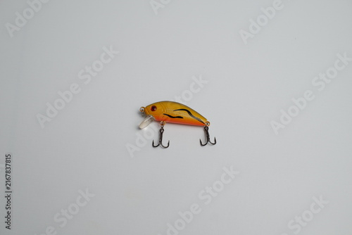 Quadro su tela Bright orange yellow artificial fishing lure with sharp double hooks, isolated against a clean white background