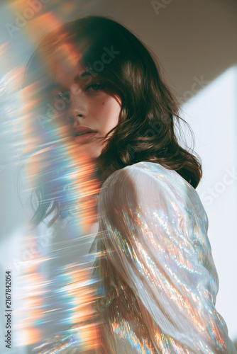ethereal female brunette model with refracting rainbow light in iridescent silver fashion 