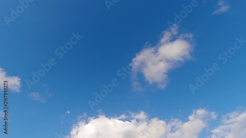 Dynamic time-lapse of white fluffy clouds moving away to reveal a clear, bright blue sky. Provides excellent negative space for commercial text overlays.