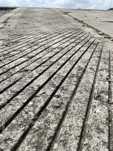 Grooved concrete ramp surface textured with parallel non slip lines suitable for safety pavement backgrounds.