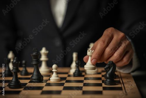 Fotografía business hand moving a white chess rook on wooden board