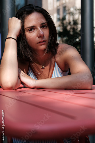Canvas Print Young woman contemplating while sitting at outdoor pink table