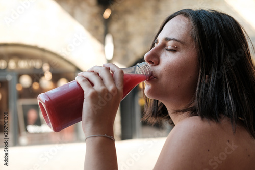 Canvas Print Woman enjoying refreshing healthy juice from bottle urban setting