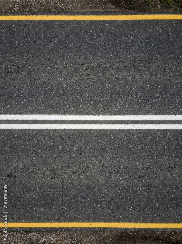 Fototapeta premium Top View of Dark Asphalt Road Surface with Double White Center Lines and Yellow Edge Markings