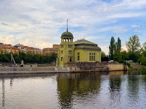 Fotografía Old building by the river with trees and clouds in the background