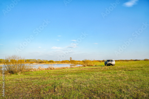 Old van parked in a green field near a lake
