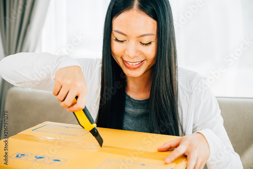 Foto A woman uses a utility cutter for precision unboxing revealing contents of a shopping cardboard box