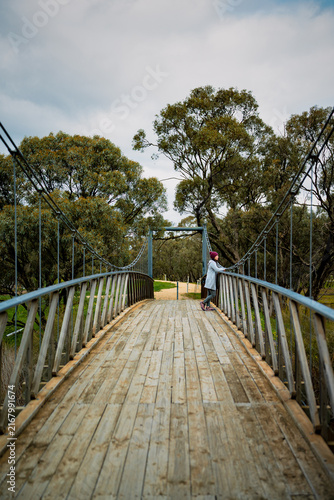 Side view of a woman standing on a timber suspension bridge and enjoying the nature, Donald, Victoria, Australia