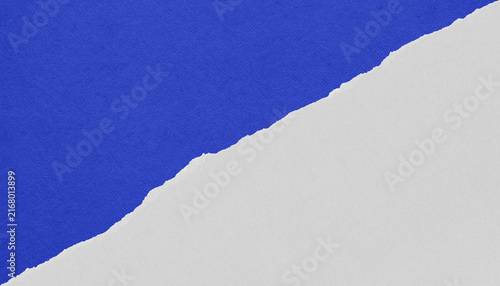 Torn blue paper on white background with an irregular diagonal edge and ample copy space, ideal for collage, editorial design, advertising and banners.