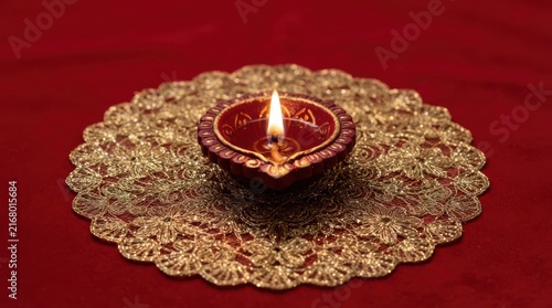 Single burning oil lamp on gold lace doily for Diwali celebration