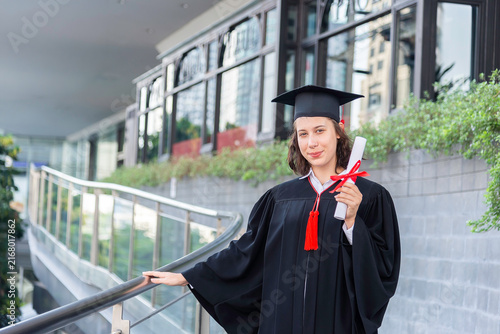 Happy young woman with diploma on graduation day