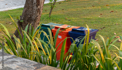 Canvastavla Colorful recycling bins for food, plastic, and glass waste in a park