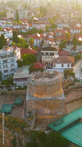 Vertical video. Antalya, Turkey. Hidirlik Tower, a cylindrical Roman stone structure on a square base, aerial view at sunrise over Kaleici Old Town and the Mediterranean cliff edge. Aerial View, Depa