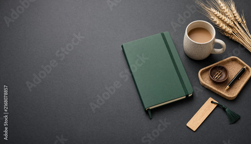Green notebook with coffee cup and stationery on a dark grey background