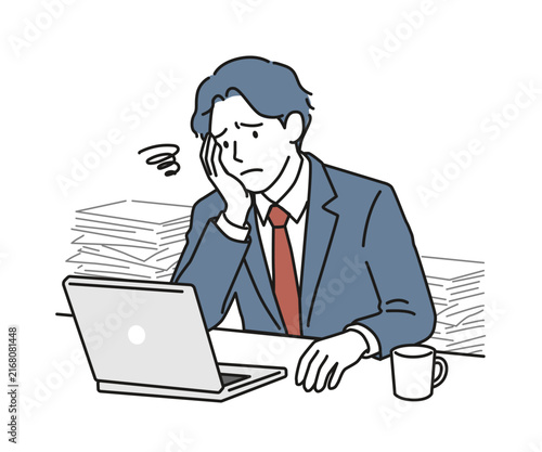 山積みの書類とノートPCの前で頭を抱えて悩む男性ビジネスパーソン（疲労・残業・過重労働）