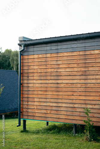 Принти на полотні The structure features a wooden facade with horizontal planks and a clean design, situated in a green area