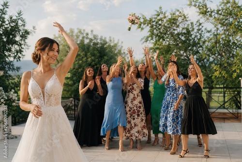 a bride throwing flowers to woman friends