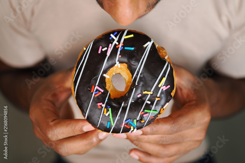 Fotografie Person holding a donut and getting ready to eat