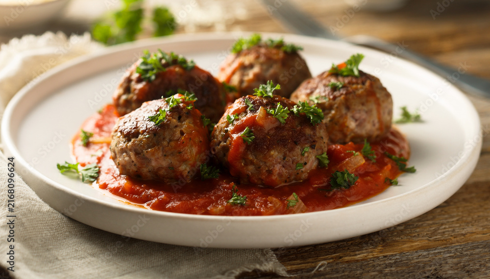 Fototapeta premium Delicious homemade meatballs served with fresh tomato sauce on a white plate.