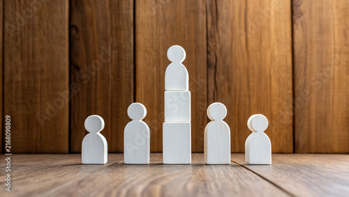 Minimalist white figurines representing teamwork and leadership on wooden background
