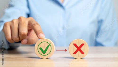Person Selecting Green Checkmark Over Red Cross on Wooden Discs Representing Decision Making, Choice Selection, True or False Test, and Positive Approval