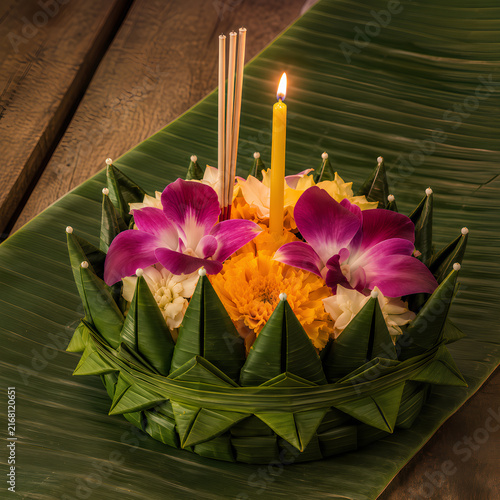 Traditional Thai Krathong made of folded banana leaves decorated with colorful flowers, a lit candle, and incense sticks for the Loy Krathong festival.