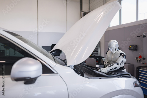 A humanoid robot is meticulously examining and repairing the engine of a modern vehicle in a well-lit garage setting