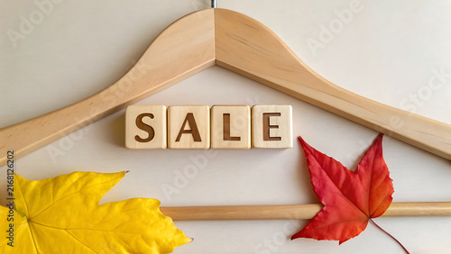 Wooden hanger with SALE sign and autumn leaves for retail discount promotion display